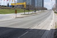 an empty road with some buildings and flags on the sidewalk nearby it are also in the distance