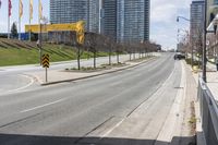 an empty road with some buildings and flags on the sidewalk nearby it are also in the distance