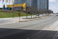 an empty road with some buildings and flags on the sidewalk nearby it are also in the distance