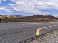 an empty road on a sunny day with mountains in the background in an arid area