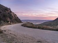 the road in the mountains is empty during a sunset scene, which looks out over the valley below