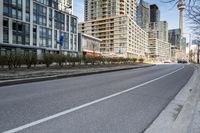 the paved road in front of tall buildings is empty of people and traffic signs from nearby