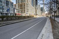 the paved road in front of tall buildings is empty of people and traffic signs from nearby