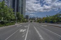 the empty road with no vehicles on it is surrounded by tall buildings and trees in the distance