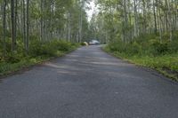 a white vehicle sitting in the middle of an empty road next to green bushes and trees