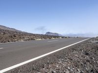 a road near the mountain side in the foggy sun day, and on the opposite bank are hills