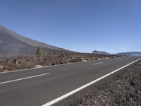 a road near the mountain side in the foggy sun day, and on the opposite bank are hills