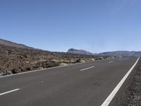 a road near the mountain side in the foggy sun day, and on the opposite bank are hills