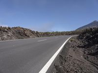 an empty road with no cars on it going through a mountain area with hills on either side