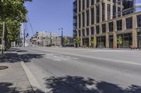 the empty road is going through an intersection in a large city center with lots of glass windows