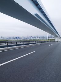an empty highway and highway with city skylines in the background, in front of grey skies