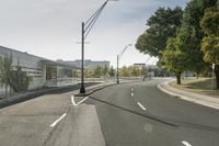 a empty road with street lamps along the side of it that are green trees and some building on both sides