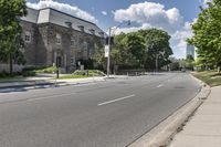 there is a street with an empty road near some buildings and trees in the background