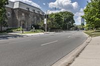 there is a street with an empty road near some buildings and trees in the background