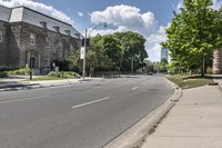 there is a street with an empty road near some buildings and trees in the background