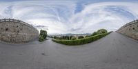 a fish eye lens of an empty road in italy on the left, a bridge in the right