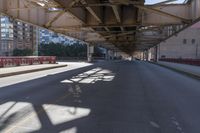 a empty road under a bridge in a city at low hours before the sun goes down