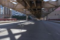 a empty road under a bridge in a city at low hours before the sun goes down