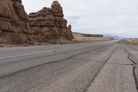 an empty road in the middle of the desert with rocks on both sides and mountains behind it