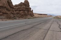 an empty road in the middle of the desert with rocks on both sides and mountains behind it