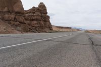 an empty road in the middle of the desert with rocks on both sides and mountains behind it