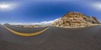 a fish - eye lens view of an empty road with a mountain in the background