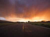 an empty road with a yellow line at sunset in a rural setting on the horizon