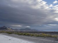 there is an empty road beside a mountainside, with a mountain in the distance