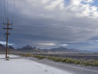 there is an empty road beside a mountainside, with a mountain in the distance