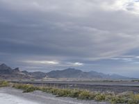 there is an empty road beside a mountainside, with a mountain in the distance