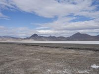 the empty road goes down into the vast plain in front of a mountain range and snow capped mountains