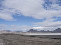 the empty road goes down into the vast plain in front of a mountain range and snow capped mountains