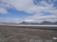 the empty road goes down into the vast plain in front of a mountain range and snow capped mountains