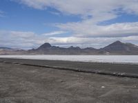 the empty road goes down into the vast plain in front of a mountain range and snow capped mountains