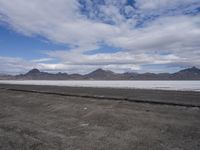 the empty road goes down into the vast plain in front of a mountain range and snow capped mountains