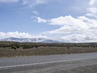 a motorcycle is sitting next to an empty road with mountains in the background on a sunny day