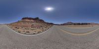 an empty road stretches into the sky near a mountain range and the sun shines on the horizon