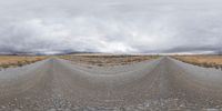 a photo looking at a straight empty road under cloudy skies in the middle of nowhere