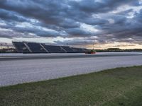 the road between two rows is empty during a cloudy day in the nascar stadium's parking lot