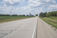 the empty road leads toward the wind turbine farm on the other side of it with no clouds in the sky