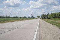 the empty road leads toward the wind turbine farm on the other side of it with no clouds in the sky