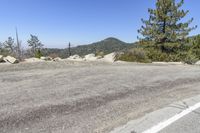 an empty road by the woods and the edge of a mountain range with boulders on either side