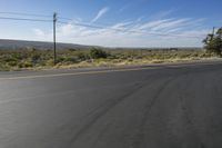 the empty road is wide and winding by the mountains on the horizon, with trees in the background