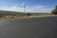 the empty road is wide and winding by the mountains on the horizon, with trees in the background