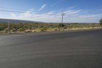 the empty road is wide and winding by the mountains on the horizon, with trees in the background