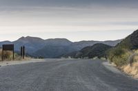 there is an empty road in the woods with mountains in the back ground and no people on it