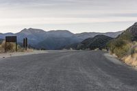 there is an empty road in the woods with mountains in the back ground and no people on it