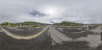 the 360 - view shows two empty road in a large town with houses, buildings and mountains in the distance