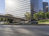 the empty roadway with some buildings in the background and a bridge across the road with grass in front