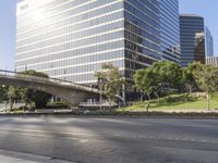 the empty roadway with some buildings in the background and a bridge across the road with grass in front